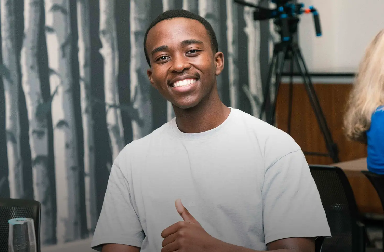 Smiling man in white shirt showing thumbs up